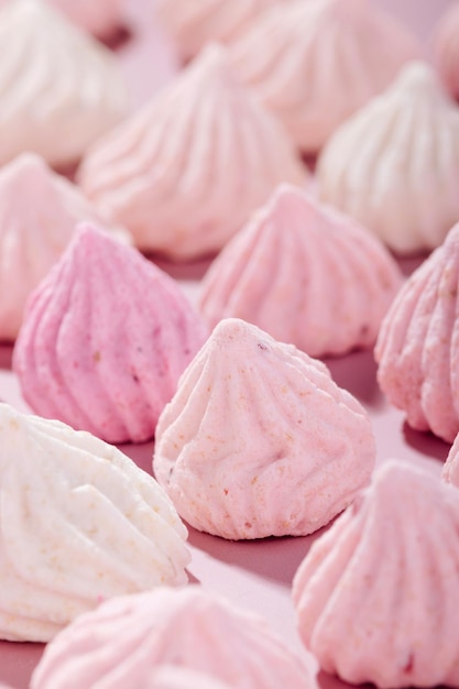 Biscoitos de merengue rosa com sabor de frutas vermelhas em um fundo rosa