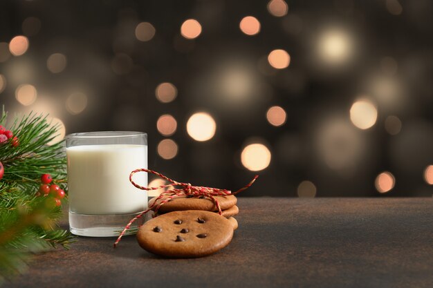 Biscoitos de Natal e copo de leite para o Papai Noel perto da árvore de Natal