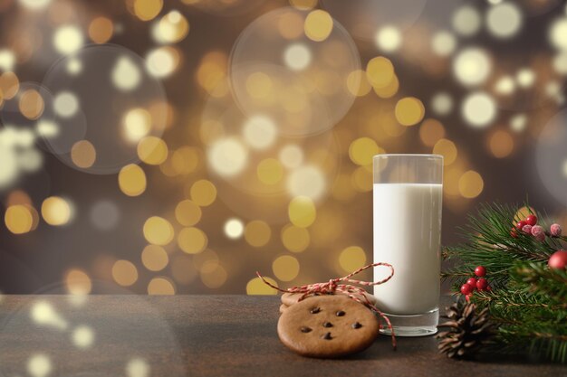 Biscoitos de natal e leite para papai noel em vidro perto da árvore de natal.  cartão de natal. | Foto Premium