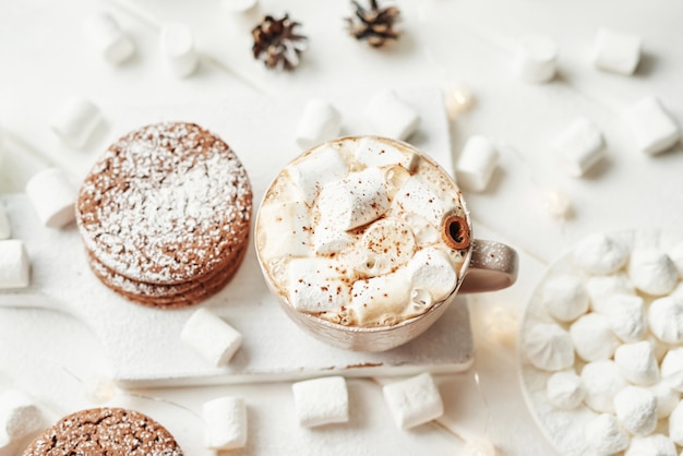 Biscoitos de natal, leite, cacau, marshmallows, prato de merengue pela janela