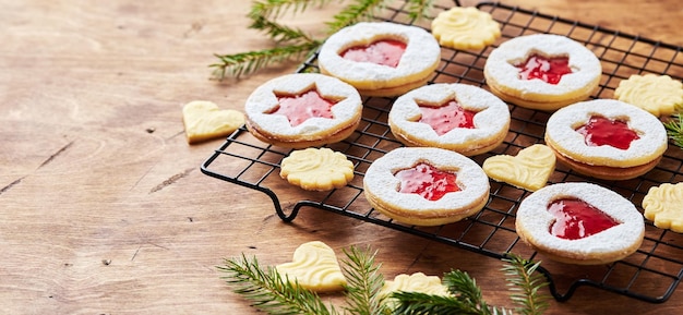 Foto biscoitos de natal linzer clássicos com geléia de framboesa ou morango na mesa de madeira