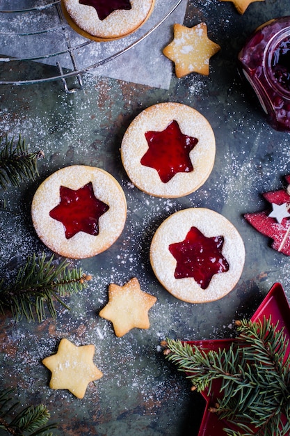 Biscoitos de Natal Linzer com geléia de framboesa no fundo da mesa verde.