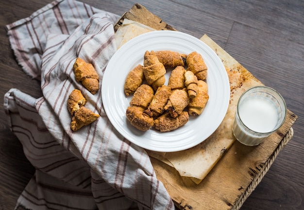 Biscoitos de pães de queijo em pãezinhos de pastelaria curtos, leite, sobremesa em uma madeira