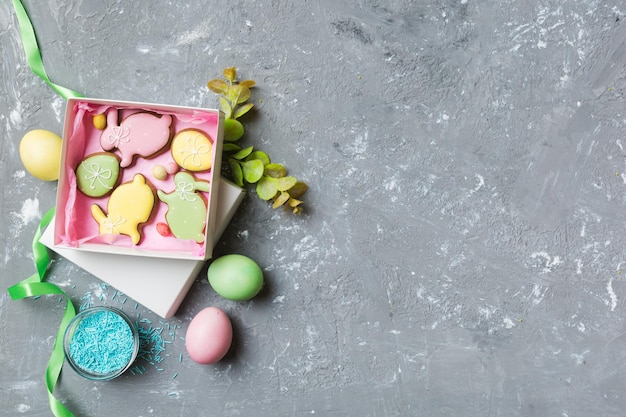 Biscoitos de páscoa coloridos na cesta com ovos de páscoa multicoloridos em fundo colorido Conceito de férias de ovos de páscoa de cor pastel com espaço de cópia