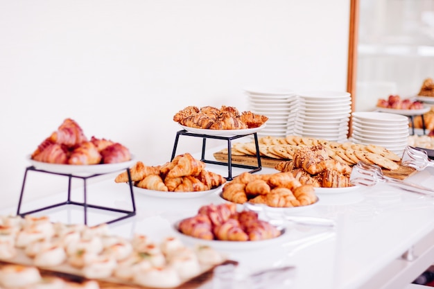 Biscoitos de pastelaria e croissants sobremesas doces servidas em bebidas alimentares de evento de caridade e conceito de menu a ...