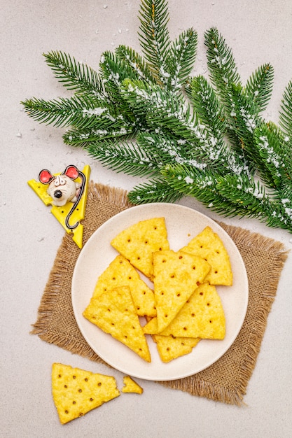 Biscoitos de queijo festivo, conceito de lanche do ano novo. Biscoitos, figura de rato, galho de árvore do abeto, neve artificial, guardanapo de pano de saco.