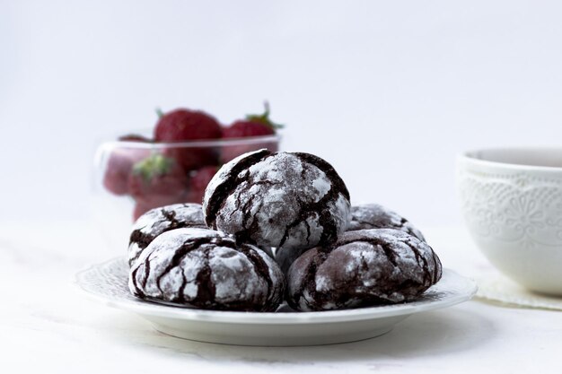 Biscoitos de rachaduras de chocolate em uma mesa de mármore branca Biscoitos deliciosos uma xícara de chá e morangos