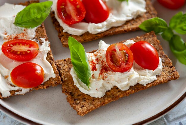 Biscoitos de tomate orgânico sem glúten com tomates frescos e sem lactose espalhados sobre fundo de cerâmica.