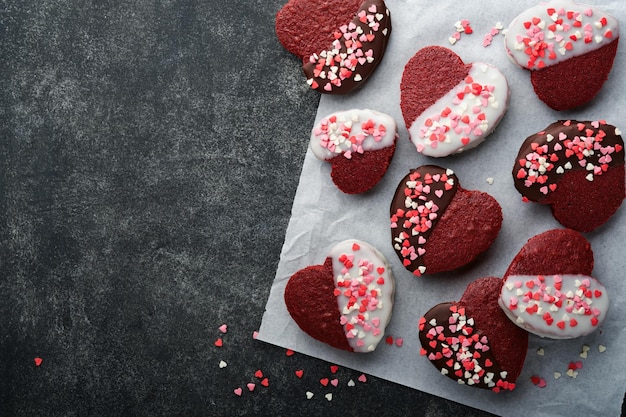 Biscoitos de veludo vermelho ou brownie em forma de coração em cobertura de chocolate com rosas vermelhas em fundo preto Ideia de sobremesa para Dia dos Namorados Mães ou Dia das Mulheres Sobremesa caseira Bolo para Dia dos Namorados