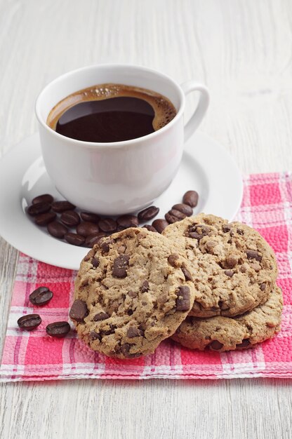 Biscoitos deliciosos e uma xícara de café quente em uma mesa de madeira leve