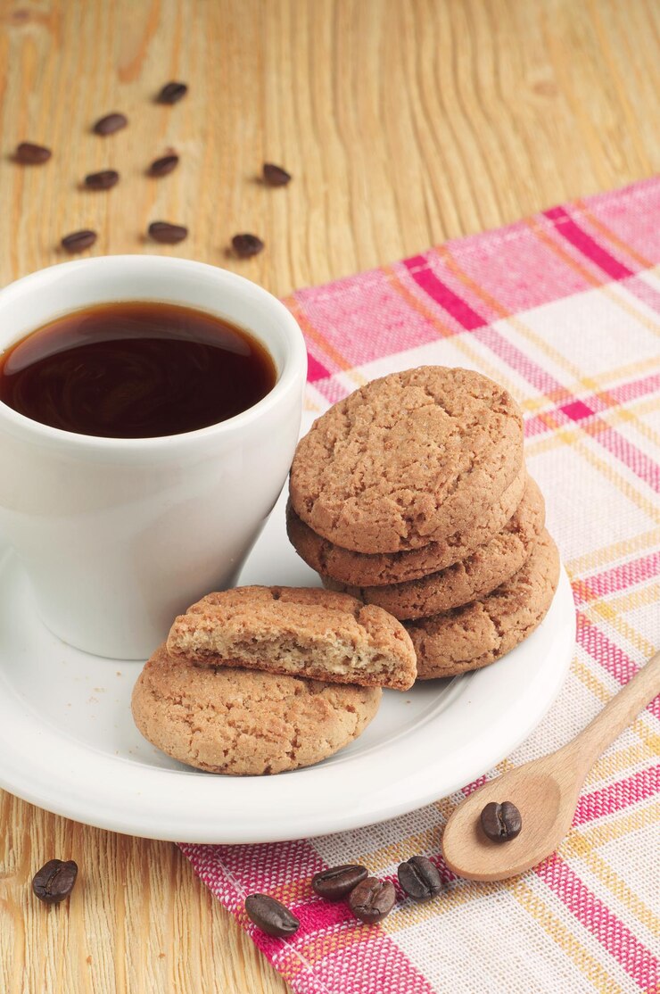 Biscoitos deliciosos e uma xícara de café quente na mesa de madeira