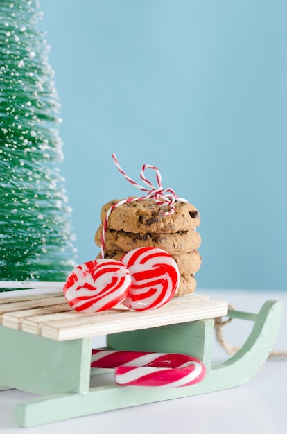 Biscoitos e doces de natal em trenó de madeira com árvore