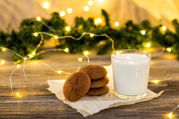 Biscoitos e leite em copo para o papai noel em frente a um bokeh de luz de natal