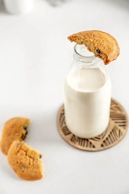 Biscoitos e leite em uma garrafa em uma mesa branca com um guardanapo