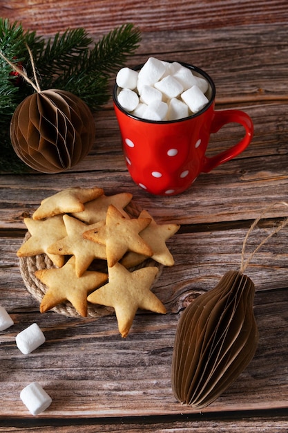 Biscoitos em forma de estrela de Ano Novo feitos em casa ao lado de uma caneca vermelha de marshmallow