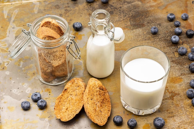 Biscoitos em uma jarra de vidro e sobre a mesa Leite em um copo e em uma garrafa