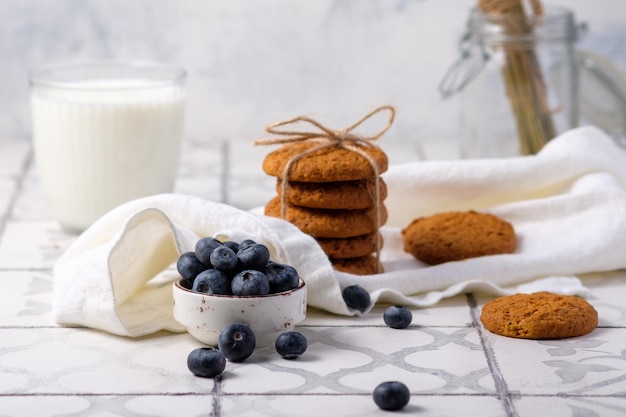 Biscoitos frescos de aveia de avós com leite e bagas num guardanapo de linho na aldeia