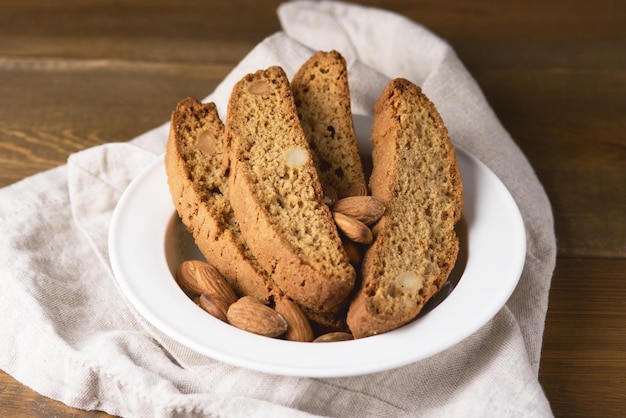 Biscoitos italianos saborosos com tigela branca de amêndoa com deliciosos biscoitos Cantucci Comida italiana de madeira