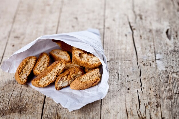 Biscoitos italianos tradicionais cantuccini no saco de papel branco na mesa de madeira rúctil