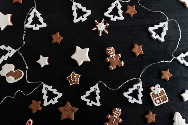 Biscoitos pintados com vidros de Natal na vista superior de fundo preto.