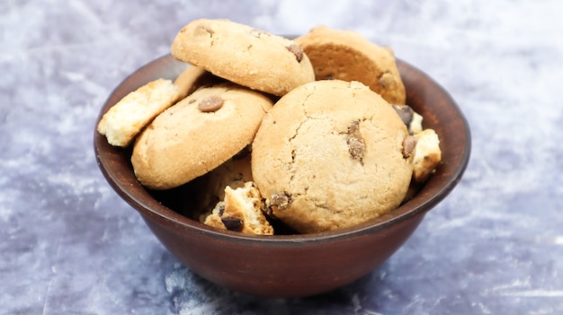 Biscoitos recém-assados macios com gotas de chocolate em um prato de barro marrom no mármore cinza. pastelaria doce tradicional americana, deliciosa sobremesa caseira. fundo culinário.