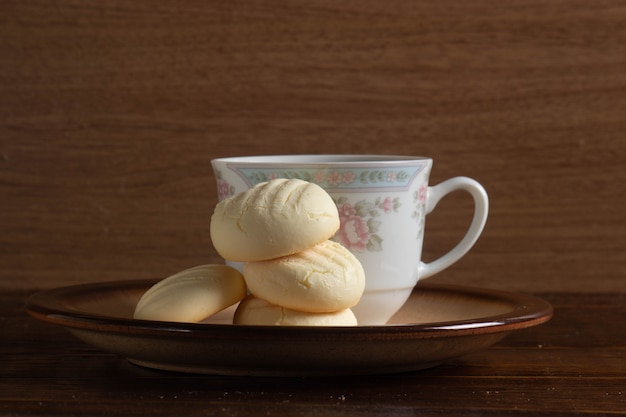 Biscoitos redondos pequenos e uma xícara de café em um prato marrom