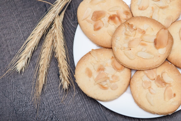 Biscoitos saborosos biscoitos com amêndoa e trigo na placa no fundo de madeira