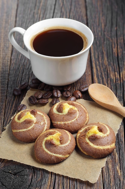 Biscoitos saborosos com chocolate e café quente na mesa escura