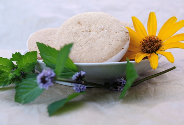 Biscoitos saborosos em um pires com folhas de hortelã e flor amarela