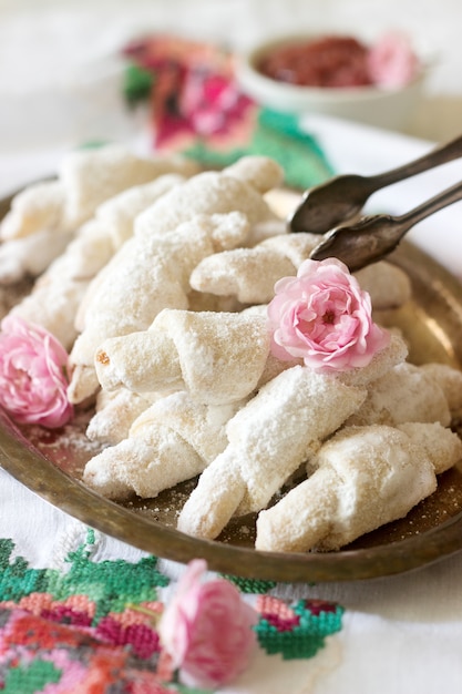 Biscoitos tradicionais romenos ou moldavos de biscoito com recheio de geléia e uma xícara de chá sobre o fundo claro.