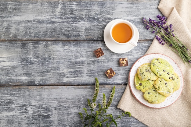 Biscoitos verdes com chocolate e hortelã com uma xícara de chá verde no espaço de cópia de vista superior de fundo de madeira cinza