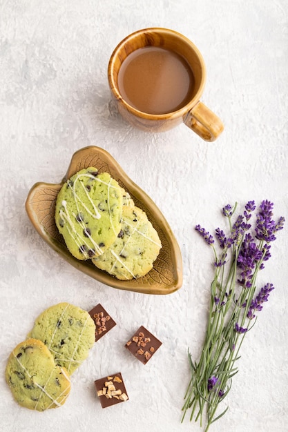 Biscoitos verdes com chocolate e menta com uma xícara de café na vista superior de concreto cinza