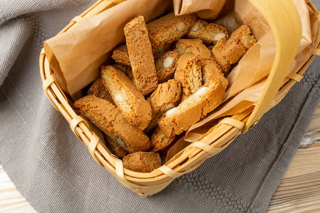 Biscotti di prato em fundo de serapilheira de toalha de mesa rústica. Cookies de nozes de cantuccini italianos tradicionais. Bolinho caseiro de cantucci com amêndoa em uma cesta de vime