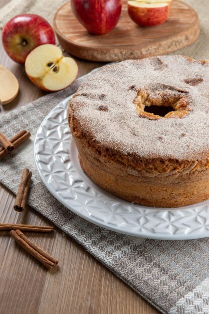 Biskuitkuchen oder Chiffon-Kuchen mit Äpfeln, die so weich und köstlich sind, in Scheiben geschnitten mit Zutaten Zimt Eier Mehl Äpfel auf Holztisch Hausbäckerei Konzept für Hintergrund und Tapete