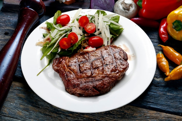 Bistec asado con ensalada de tomate cherry y lechuga y parmesano rallado