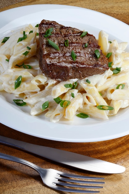 Bistec asado con penne en salsa blanca