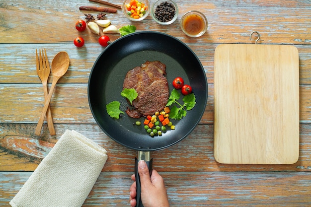 Bistec Black Angus a la parrilla en sartén de hierro grill sobre fondo de madera