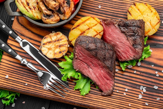 Bistec de buey con salsa de pimienta y verduras a la parrilla en una tabla de cortar