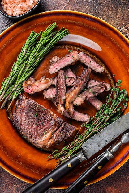 Bistec de carne de ternera a la parrilla en rodajas o chuletón en un plato rústico en negro. Vista superior.