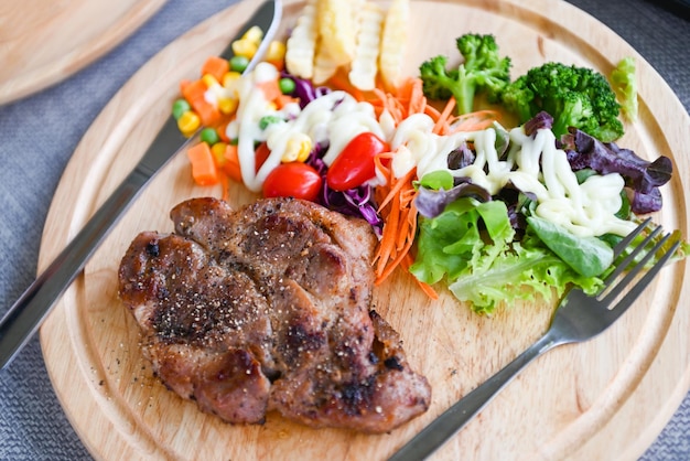 Bistec casero con papas fritas y ensalada de verduras frescas en bandeja de madera menú de bistec saludable