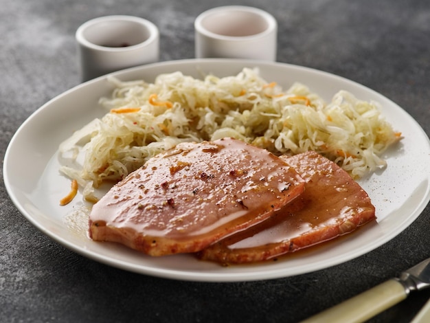 Bistec de cerdo Kasseler respaldado con chucrut León de cerdo ahumado Chuleta de cerdo ahumada en rodajas sobre tabla de madera