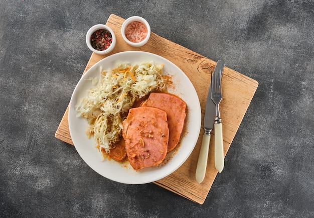 Bistec de cerdo Kasseler respaldado con chucrut León de cerdo ahumado Chuleta de cerdo ahumada en rodajas sobre tabla de madera