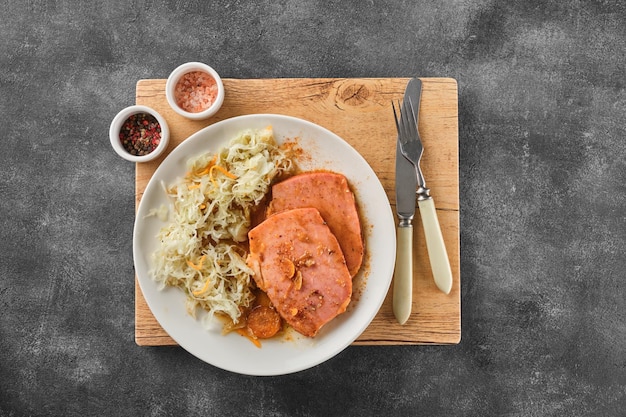 Bistec de cerdo Kasseler respaldado con chucrut León de cerdo ahumado Chuleta de cerdo ahumada en rodajas sobre tabla de madera