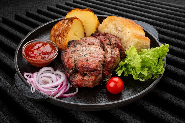 Bistec de cerdo a la parrilla con matnakash de papas al horno y salsa roja Servido en una sartén de hierro fundido