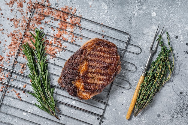 Bistec de chuletón a la parrilla con carne de ternera a la parrilla con hierbas Vista superior de fondo gris