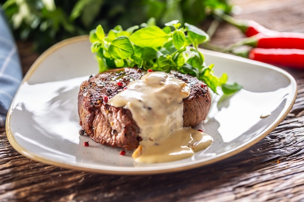 Bistec cocido con salsa de champiñones y ensalada verde al lado.