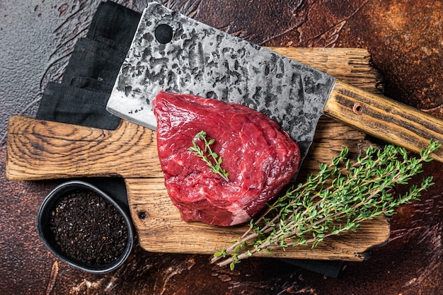 Foto bistec crudo en una tabla de corte de carnicero fondo oscuro vista superior