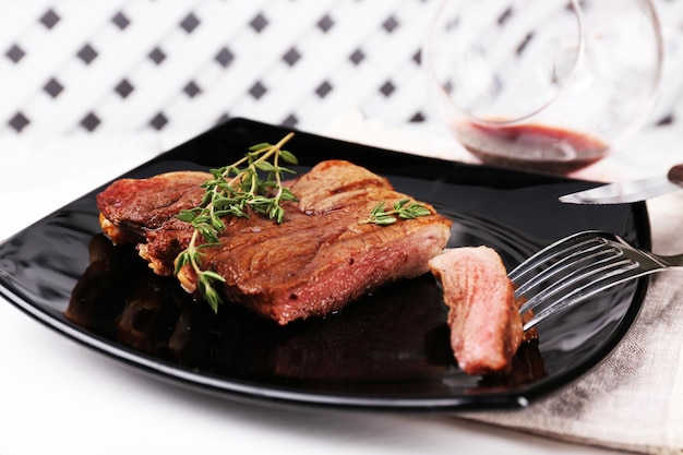 Bistec con hierbas en un plato con vino sobre fondo de madera