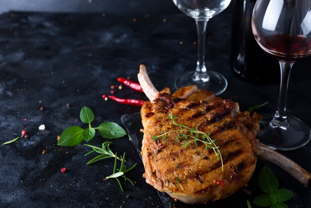 Bistec de hueso de T con un vaso y una botella de vino en la mesa de piedra.