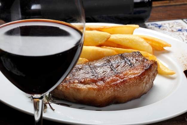 Bistec con papas fritas y vino tinto